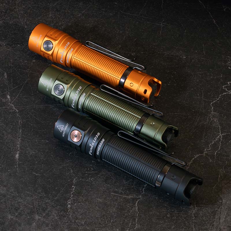 Three Fenix LD30 flashlights in orange, green, and black on a dark textured surface